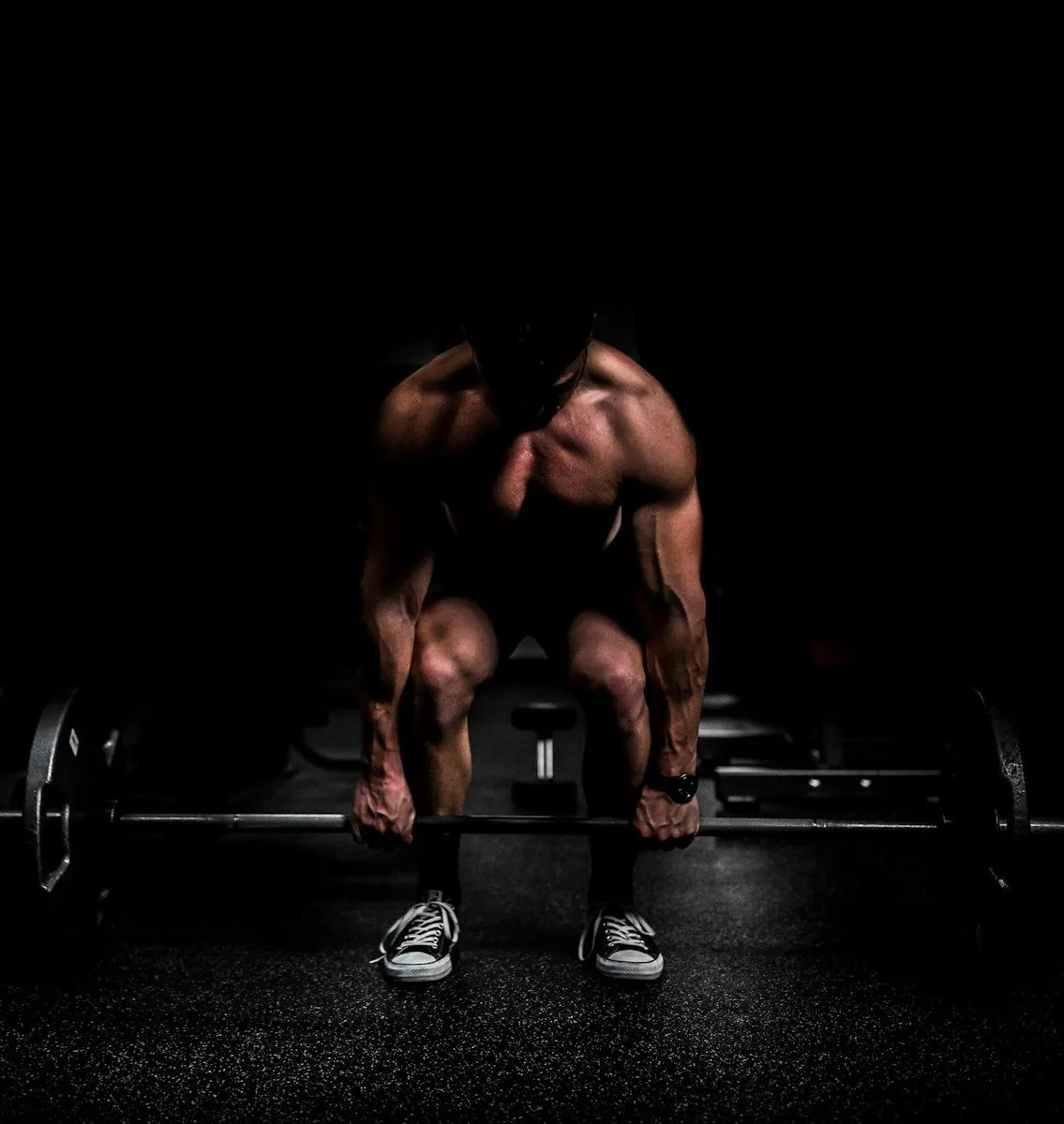 Lifter crouched over a loaded bar in near-darkness
