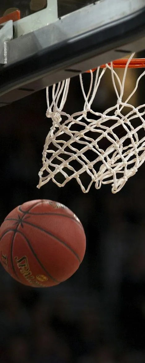 Basketball dropping through the net in an arena, crowd lights blurred behind