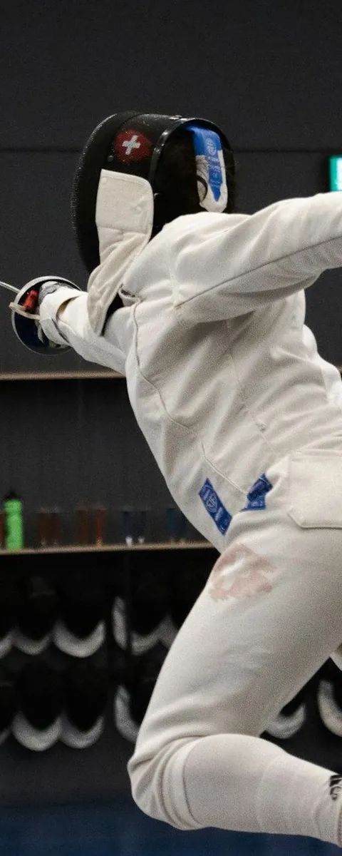 Fencer lunging in a dark salle